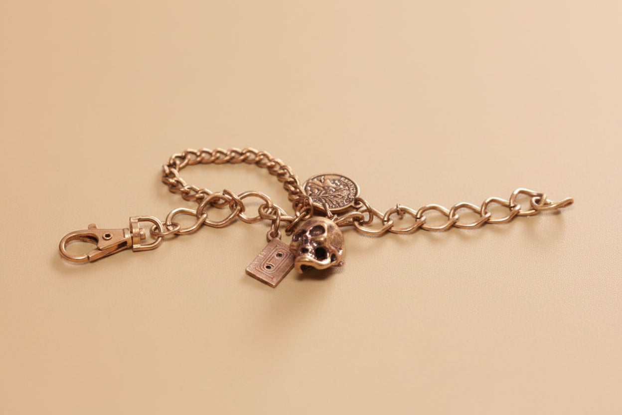 Vintage Gold Tone Charm Bracelet with Skull, Cassette, and French Coin Charms