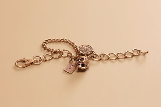 Vintage Gold Tone Charm Bracelet with Skull, Cassette, and French Coin Charms